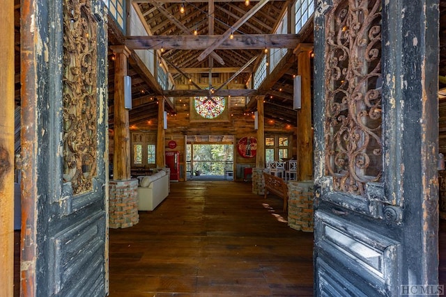 corridor with wood-type flooring, high vaulted ceiling, and wood walls