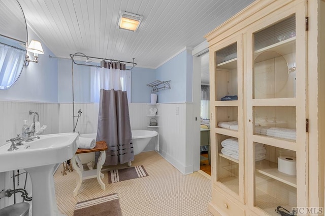 bathroom with a washtub, ornamental molding, and tile patterned floors