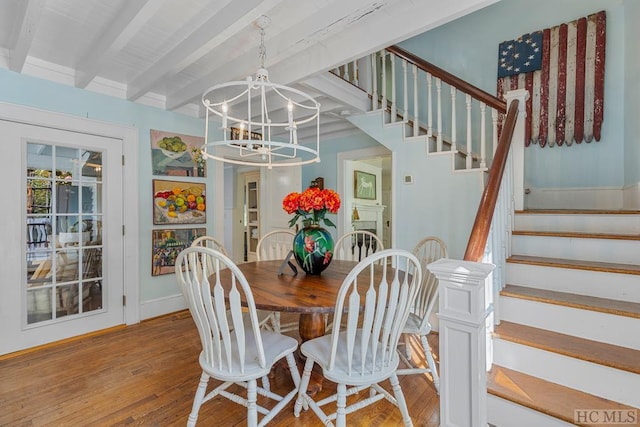 dining area with light hardwood / wood-style floors, a chandelier, and beamed ceiling