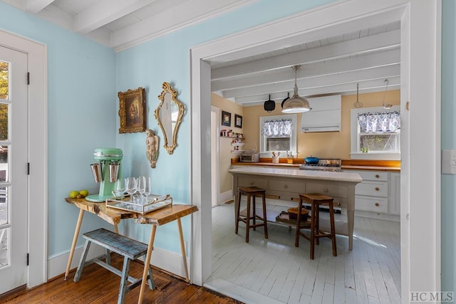 kitchen with wood-type flooring, pendant lighting, white cabinets, and beam ceiling