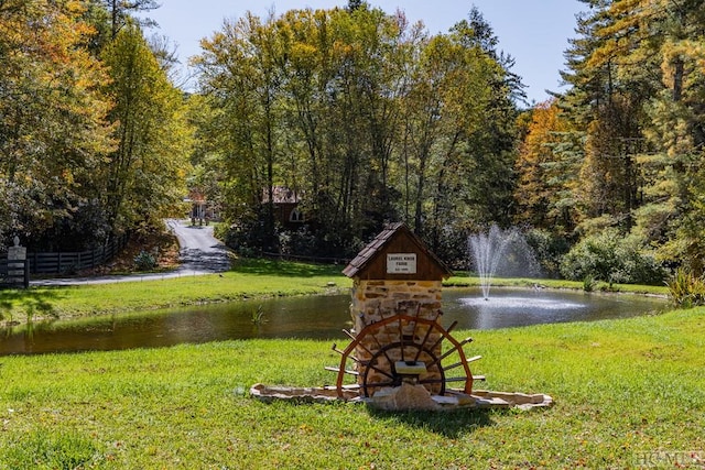 surrounding community featuring a water view and a lawn