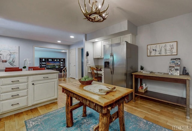 kitchen featuring white cabinetry, a chandelier, stainless steel fridge with ice dispenser, and light wood-type flooring