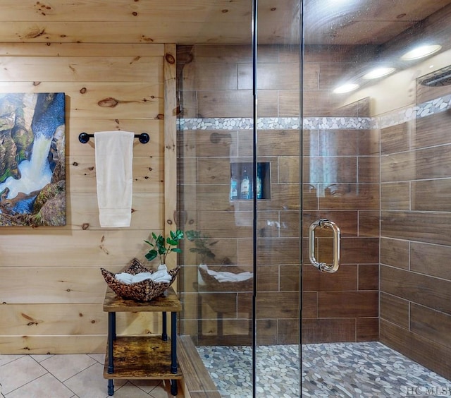 bathroom featuring wooden walls, a shower with shower door, and tile patterned flooring