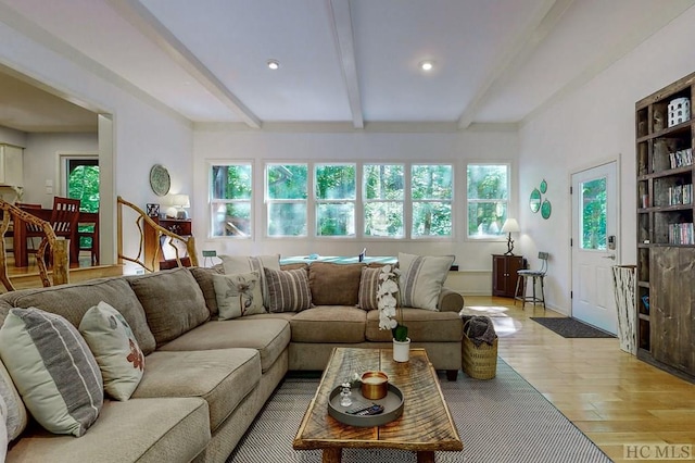 living room with beam ceiling, light hardwood / wood-style flooring, and a wealth of natural light