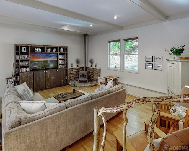 living room featuring light hardwood / wood-style floors, beamed ceiling, and a wood stove