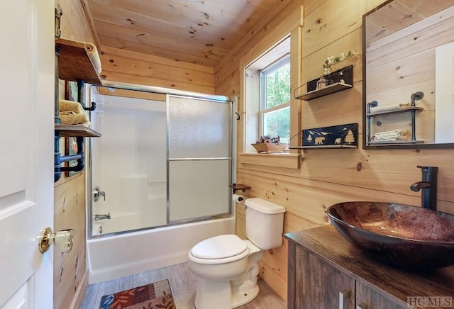 full bathroom with hardwood / wood-style flooring, bath / shower combo with glass door, wooden walls, wooden ceiling, and toilet