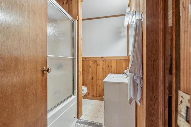 bathroom featuring tile patterned floors, wooden walls, vanity, toilet, and wainscoting