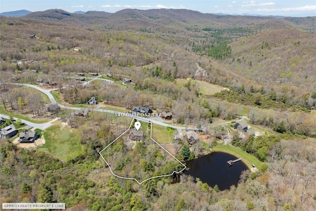 birds eye view of property featuring a water and mountain view and a wooded view