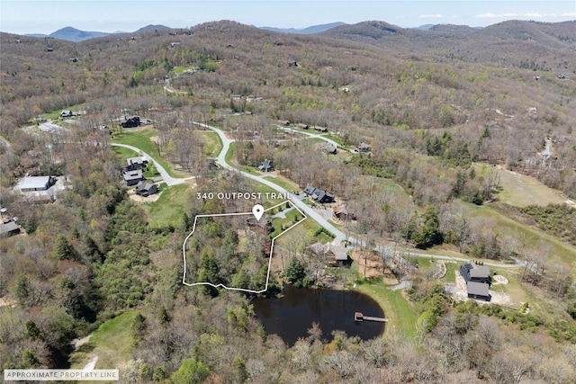 drone / aerial view featuring a water and mountain view and a view of trees