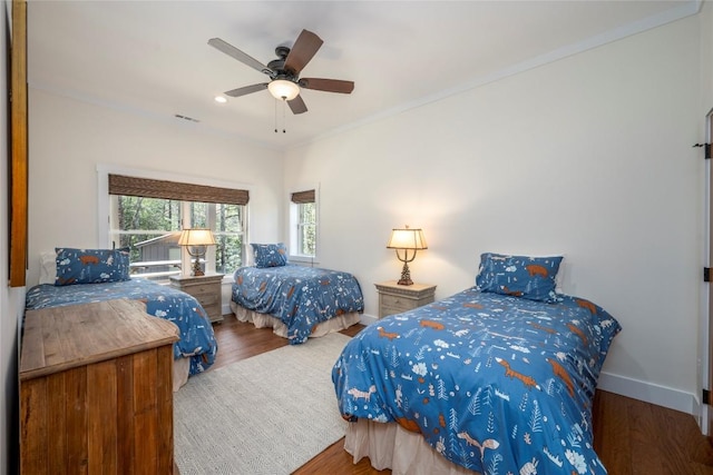 bedroom with a ceiling fan, visible vents, crown molding, wood finished floors, and baseboards