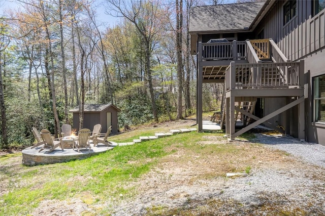 view of yard featuring a storage unit, an outdoor fire pit, a wooden deck, stairway, and an outdoor structure