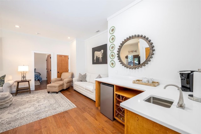 interior space with a sink, recessed lighting, light wood-type flooring, refrigerator, and ornamental molding