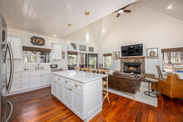 kitchen with a kitchen bar, a fireplace, freestanding refrigerator, open floor plan, and dark wood-type flooring