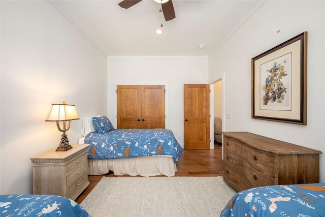 bedroom with ceiling fan, ornamental molding, a closet, and wood finished floors