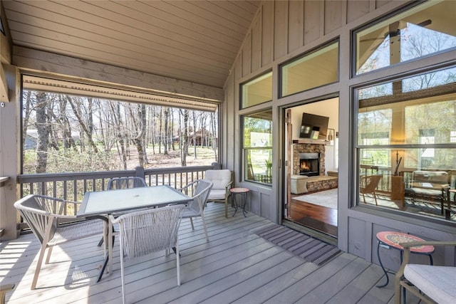 sunroom / solarium featuring outdoor dining space, a wealth of natural light, and an outdoor stone fireplace