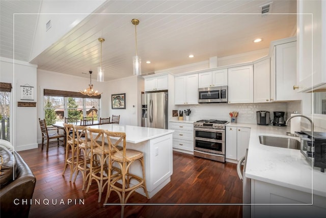 kitchen featuring crown molding, a sink, stainless steel appliances, a kitchen bar, and backsplash