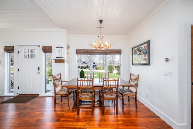 dining area with wood-type flooring, ornamental molding, and a notable chandelier