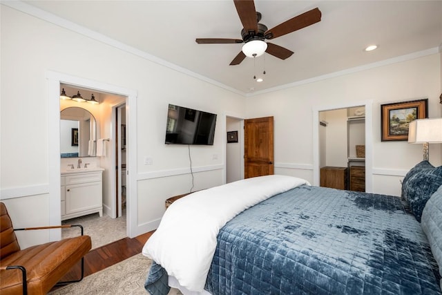 bedroom featuring crown molding, a sink, dark wood-style floors, ensuite bathroom, and recessed lighting