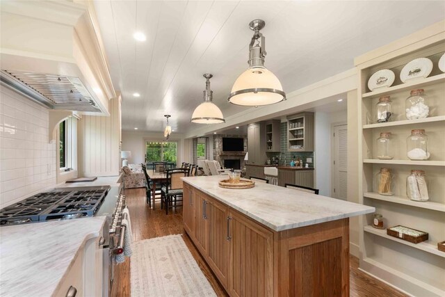 358 Jodytown Rd, Cashiers, NC 28717 - kitchen with stainless steel stove, dark wood-style flooring, a kitchen island, light stone counters, and decorative backsplash