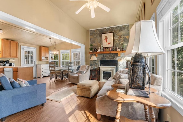 living room featuring a fireplace, ceiling fan with notable chandelier, and light hardwood / wood-style flooring