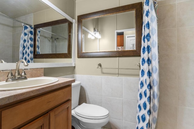 bathroom with curtained shower, toilet, tile walls, and vanity