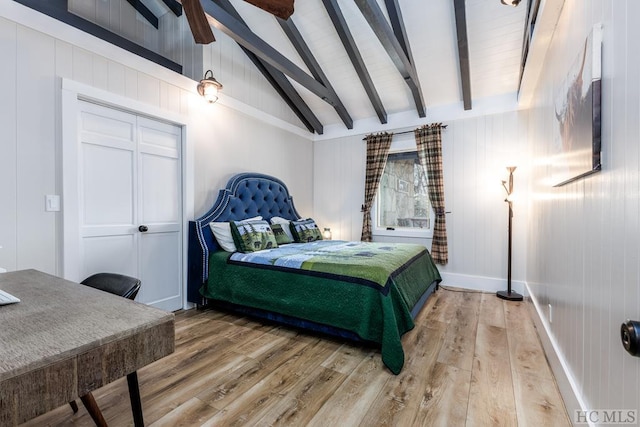 bedroom featuring ceiling fan, hardwood / wood-style floors, a closet, and vaulted ceiling with beams