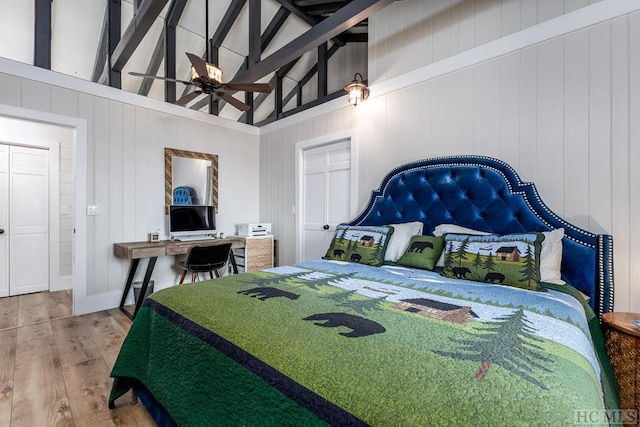 bedroom with hardwood / wood-style flooring, high vaulted ceiling, and beam ceiling