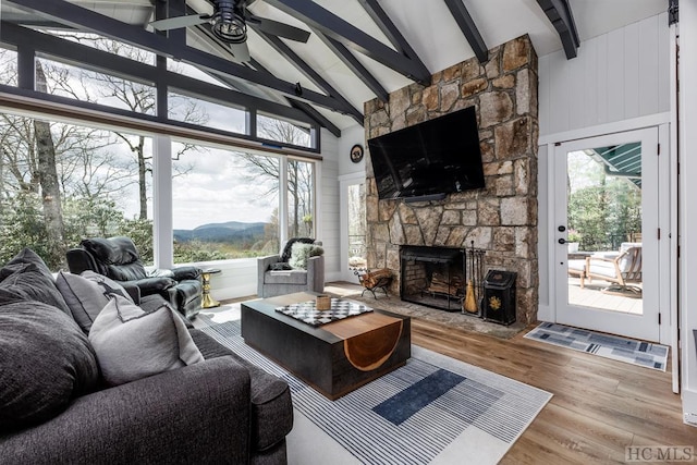 living room featuring high vaulted ceiling, a fireplace, beamed ceiling, wood-type flooring, and ceiling fan