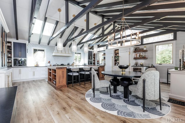 dining space featuring a chandelier, lofted ceiling with skylight, light hardwood / wood-style floors, and a healthy amount of sunlight