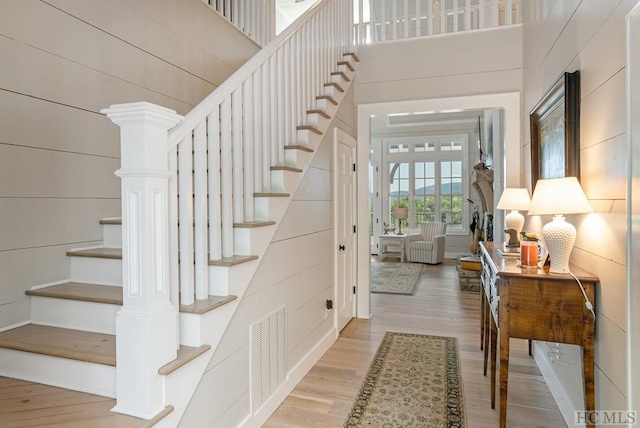 stairway with hardwood / wood-style flooring and a towering ceiling