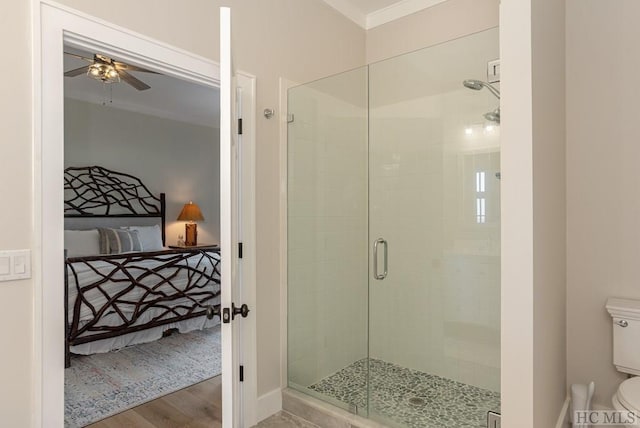 bathroom with ceiling fan, hardwood / wood-style floors, ornamental molding, toilet, and walk in shower