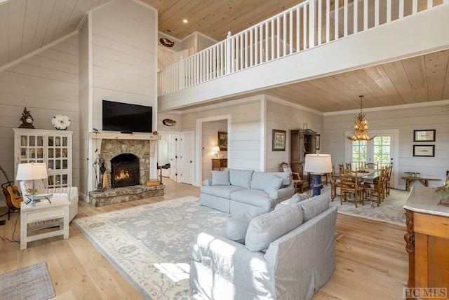 living room featuring high vaulted ceiling, light hardwood / wood-style flooring, a stone fireplace, and wood ceiling