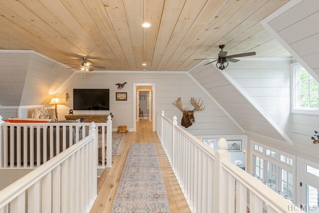 corridor featuring wood walls, lofted ceiling, wooden ceiling, and light hardwood / wood-style flooring