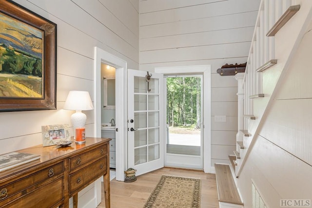 entryway with sink, light hardwood / wood-style floors, and wood walls