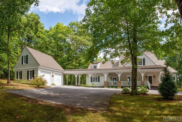 view of front of property featuring a porch, a garage, and a front yard