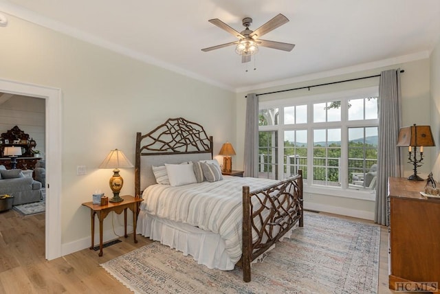 bedroom with light wood-type flooring, crown molding, and ceiling fan