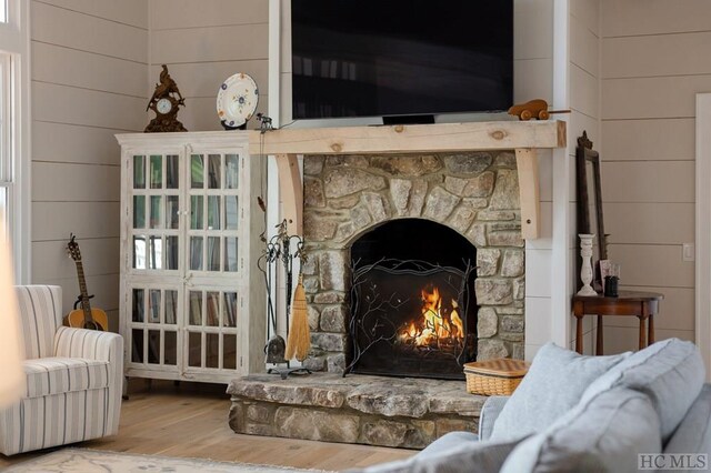 interior space featuring a stone fireplace, wood-type flooring, and wood walls