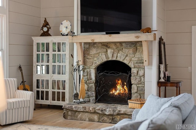 details featuring hardwood / wood-style floors, wood walls, and a stone fireplace