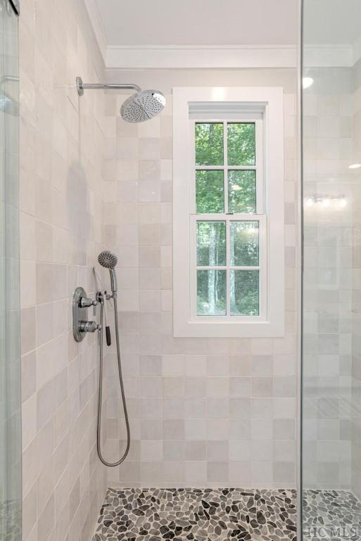 bathroom featuring crown molding and tiled shower