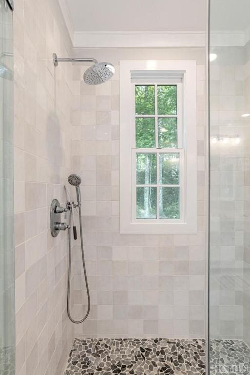 bathroom with a tile shower and ornamental molding