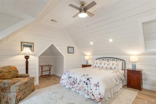 bedroom with lofted ceiling, light hardwood / wood-style flooring, wooden walls, and ceiling fan