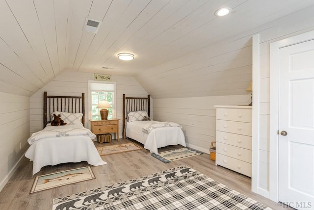 bedroom with light wood-type flooring, vaulted ceiling, wooden ceiling, and wood walls