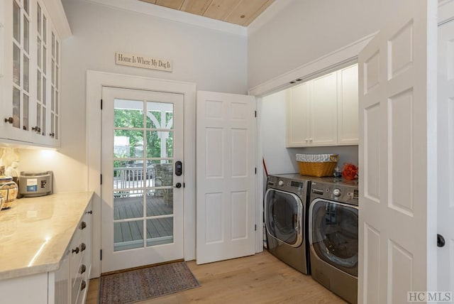 clothes washing area featuring wood ceiling, cabinets, crown molding, washer and dryer, and light hardwood / wood-style flooring