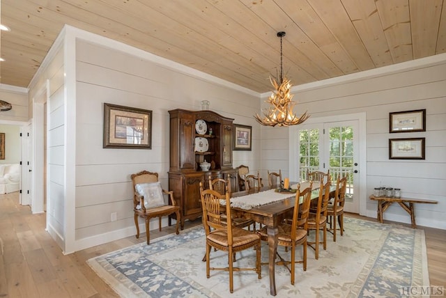 dining area with wood ceiling, light hardwood / wood-style floors, a chandelier, and wood walls