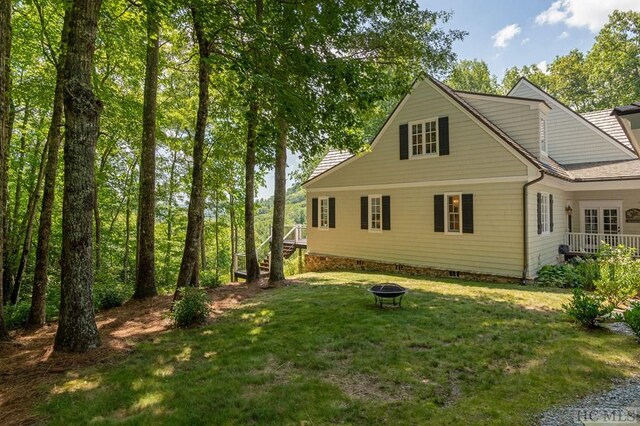 back of house with a yard and an outdoor fire pit