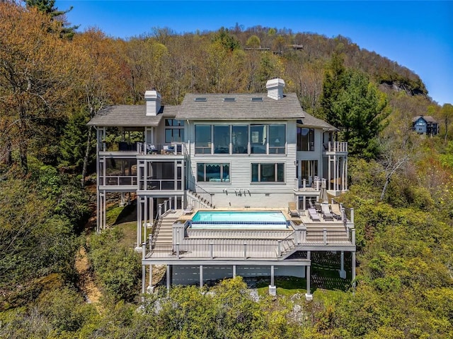 199 Mills Creek Point Rd, Lake Toxaway, NC 28747 - back of property featuring a sunroom, stairway, a view of trees, a chimney, and a balcony