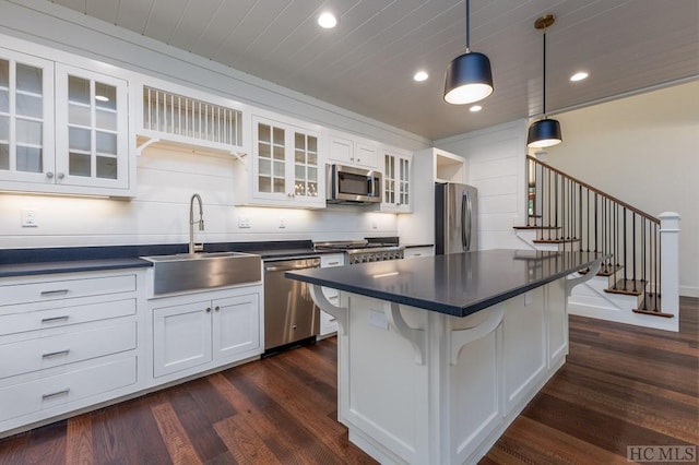 kitchen with stainless steel appliances, white cabinetry, sink, and a breakfast bar area