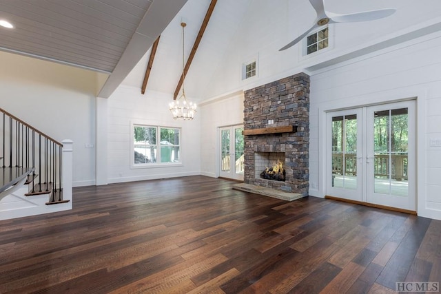 unfurnished living room with a stone fireplace, ceiling fan with notable chandelier, high vaulted ceiling, beamed ceiling, and dark hardwood / wood-style flooring