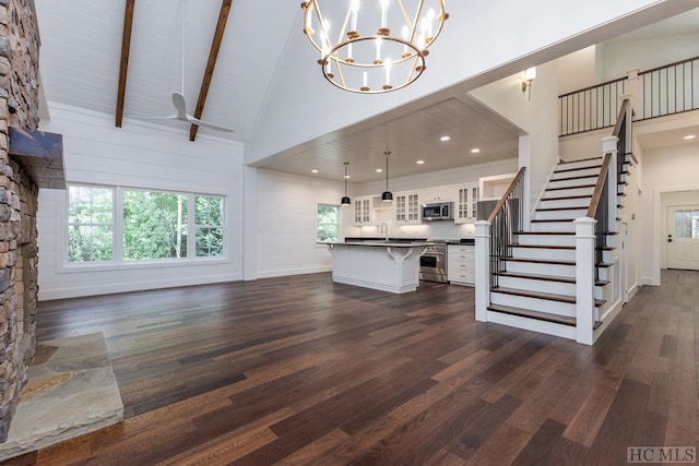 unfurnished living room featuring a notable chandelier, high vaulted ceiling, dark hardwood / wood-style floors, and beamed ceiling