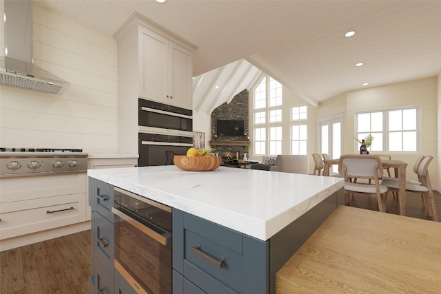 523 Broadview Dr, Highlands, NC 28741 - kitchen featuring wall chimney exhaust hood, dark wood-type flooring, vaulted ceiling, white cabinets, and a kitchen island